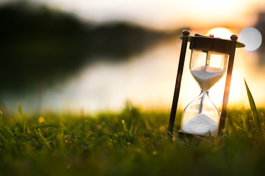 Hourglass on grass field at dawn time