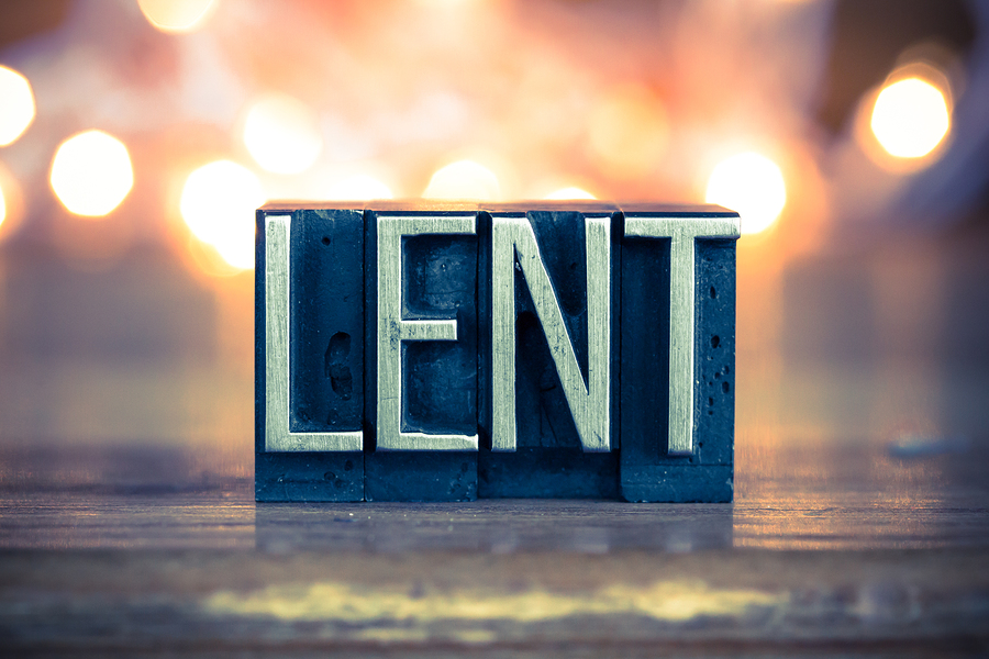 The word LENT written in vintage metal letterpress type on a soft backlit background.